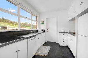 a kitchen with white cabinets and a large window at Stunning Ocean View Perfect For Groups & Families in Cooee
