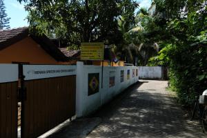 a fence next to a building with a sign on it at MENAKA HOMESTAY in Tangalle