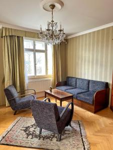 un soggiorno con divano blu e sedie di Retro Villa Prague 700sqm Indoor-Pool, Sauna, BBQ, table soccer a Praga
