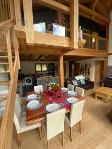 uma sala de jantar com uma mesa de madeira e cadeiras brancas em Chalet le Lotus Blanc em Les Deux Alpes