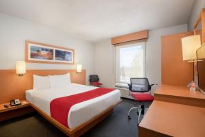 um quarto de hotel com uma cama grande e uma secretária em City Express by Marriott Tepotzotlán em Tepotzotlán
