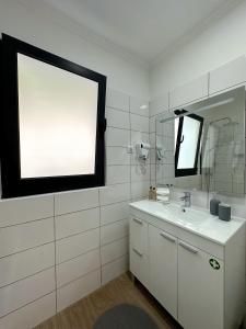 uma casa de banho branca com um lavatório e um espelho em Madeiran Sweet Home no Funchal