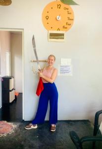 a woman holding a knife and a clock on the wall at The Orange House Weligama in Matara