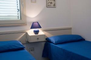 a bedroom with two beds and a lamp on a night stand at Le Bianche ville con patio privato a un passo dal mare in Torre Suda