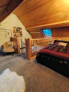 una camera con letto e soffitto in legno di Yr Hen Efail - Quirky Old Smithy cottage near forest walks, cycling & lakes a Garthbeibio