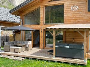 ein Holzhaus mit einer Terrasse mit einem Sonnenschirm in der Unterkunft Chalet le Lotus Blanc in Les Deux Alpes
