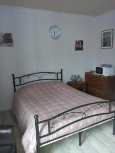 een slaapkamer met een bed en een klok aan de muur bij Studio du Parc thermal in Vittel