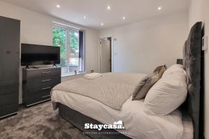 um quarto com uma cama e uma televisão de ecrã plano em Lovely Modernist 4 Bed House em Manchester