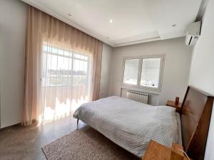 um quarto com uma cama e uma grande janela em Abilia Appart - À Proximité de l'Aéroport - Confort et Élégance em La Soukra