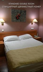 a bed in a bedroom with two lamps on a wall at Green Hotel in Atyraū