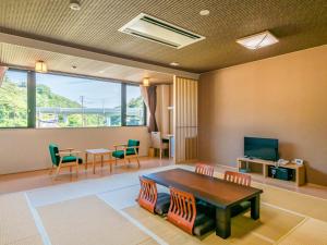 a living room with a table and chairs and a tv at 奥松島LANEホテル in Tōna