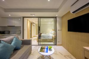 a living room with a couch and a flat screen tv at The Beachfront Hotel Phuket in Rawai Beach