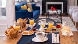 a table with breakfast foods and cups of orange juice at La Demeure Numéro 5 in Cambrai