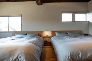 two beds in a bedroom with two windows at 海野宿一棟貸し宿 上州屋 Unnojuku Joshuya in Tomi