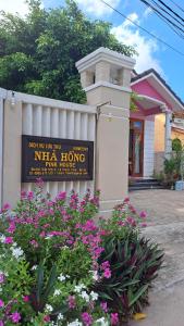 a sign in front of a building with flowers at Pink house Homestay in Hoi An