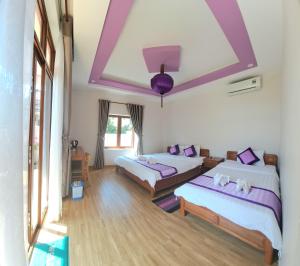 - 2 lits dans une chambre dotée de plafonds violets dans l'établissement Pink house Homestay, à Hội An