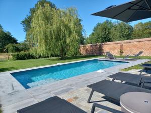 una piscina con due sedie e un ombrellone di B&B La source de notre Manon a Jauche
