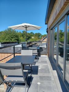 eine Terrasse mit Tischen, Stühlen und einem Sonnenschirm in der Unterkunft La source de notre Manon 