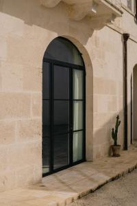 un accès à un bâtiment avec une porte noire dans l'établissement Palazzo Bergamotti, à Ostuni