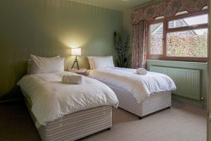 two beds in a bedroom with a window at Charming 3BD Cotswolds Family Retreat in Bourton on the Water