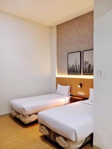 Ce lit se trouve dans un dortoir doté de draps blancs et de photos murales. dans l'établissement Hotel Andita Syariah, à Surabaya