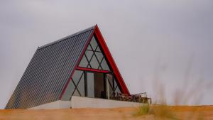 a building with a red roof on top of a field at Moon Light Camp in Bidiyah