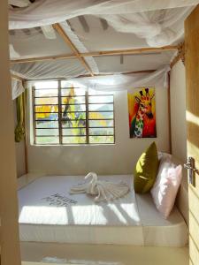 un letto bianco in una stanza con finestra di Villa Upendo Paje a Paje