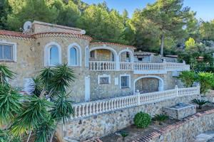 an old stone house with a fence and trees at Isabella in Denia