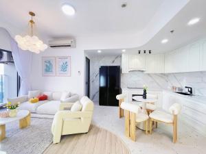 a living room with white furniture and a kitchen at MRT Apartment In Masteri Thao Dien in Ho Chi Minh City