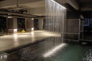 ein Gebäude mit einem Wasserpool und einem Wasserfall in der Unterkunft Cozy Flexus Signature Netflix, Pool and Privacy in Kuala Lumpur
