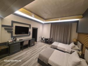 Habitación de hotel con cama, escritorio y TV. en Hisham Hotel, en Amán