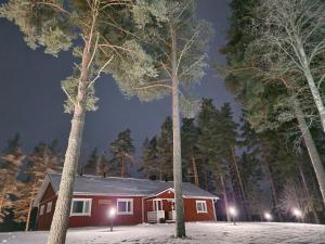 une maison dans la neige la nuit avec des arbres dans l'établissement Lomatalo Honkamäki, 