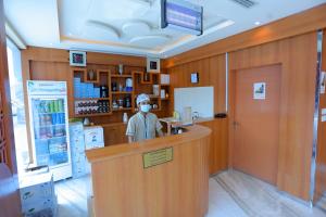 a man wearing a mask behind a counter in a pharmacy at هوستا الملقا in Riyadh
