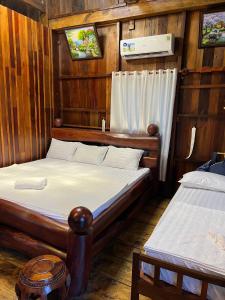カッティエンにあるCat Tien River Lodgeの木造キャビン内のベッドルーム1室(ベッド2台付)
