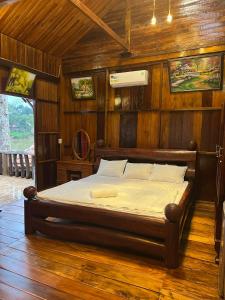 una camera con un letto in una stanza con pareti in legno di Cat Tien River Lodge a Cat Tien