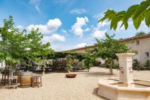 a courtyard with tables and chairs and trees at MAS PAPABIOU in Eygalières