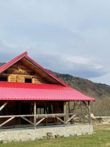 une cabane en rondins avec un toit rouge dans l'établissement Intre Barse, à Zărneşti