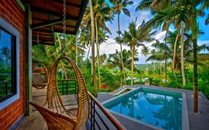 een veranda met rieten stoelen en een zwembad bij Elite Inn Cholai Lake View Resort in Taingapatam