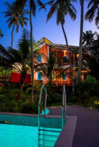 een huis met een zwembad met palmbomen bij Elite Inn Cholai Lake View Resort in Taingapatam
