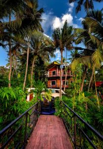 een loopbrug naar een huis met palmbomen bij Elite Inn Cholai Lake View Resort in Taingapatam