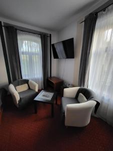 a living room with two chairs and a table and a tv at Apartamenty Amadeus in Stronie Śląskie