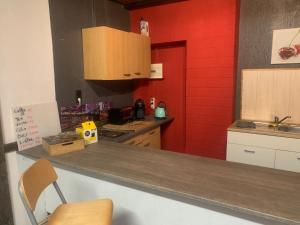 une cuisine avec un comptoir et un mur rouge dans l'établissement melissa, à Wittingen