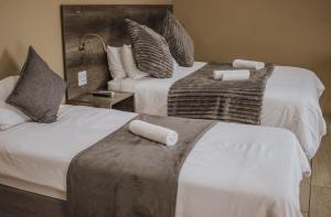 two beds in a hotel room with towels on them at Casa Leitao Lodge in Phalaborwa