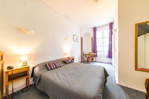 a bedroom with a bed and a desk and a mirror at Hôtel du Centre in Metz