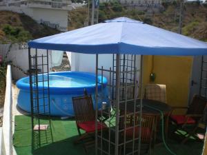 una sombrilla azul sobre una mesa y sillas junto a una piscina en Vista al Mar, en Fuengirola