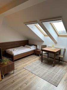 um quarto com uma cama e uma mesa e uma cama e janelas em Penzion Blatnička em Blatnička