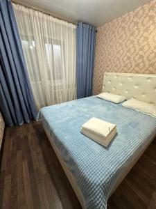 1 dormitorio con 1 cama con cortinas azules y ventana en 5 мин международный аэропорт en Prigorodnyy