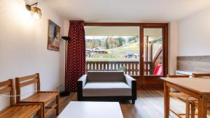 a living room with a chair and a balcony at Les Eterlous 37- Appt skis aux pieds 4 pers in Morillon