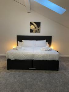 a bedroom with a large bed with two lights on it at Ascot House Apartments in Peterborough