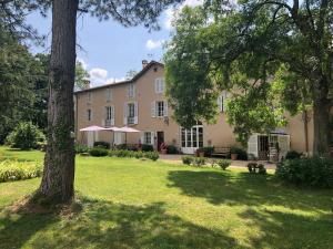 une grande maison avec une pelouse et des arbres dans l'établissement Domaine en Reynouse, à Pierreclos